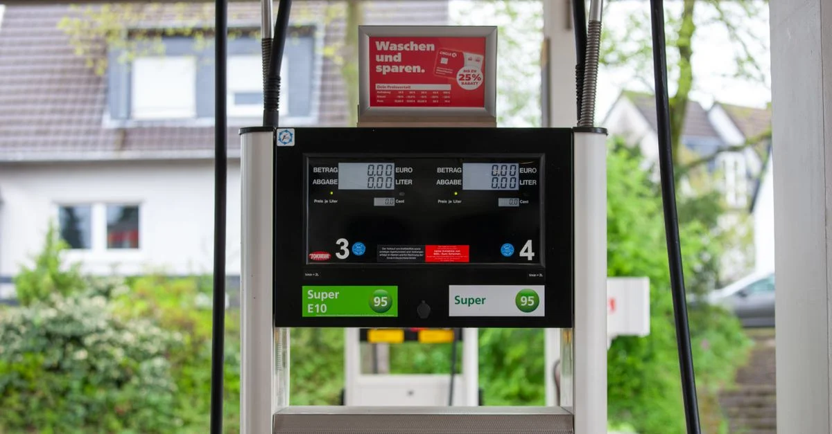 Gros plan d'une pompe à essence dans une station à Bergisch Gladbach, Allemagne, avec des maisons environnantes visibles.