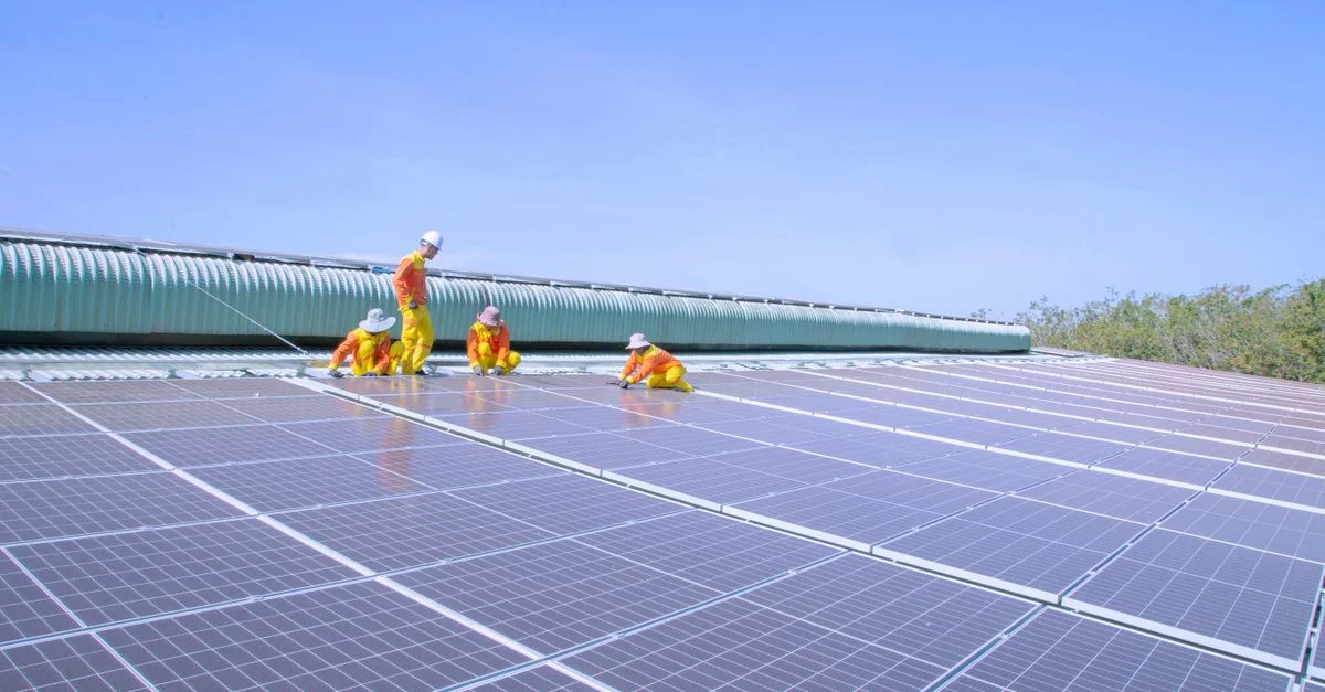 Équipe de travailleurs installant des panneaux solaires sur un grand toit, promouvant l'énergie renouvelable et la durabilité.