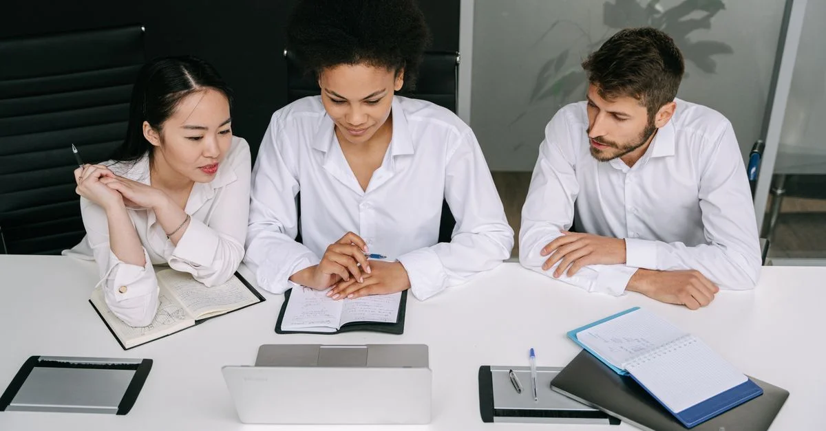 Une équipe diversifiée collabore dans un environnement de bureau moderne, concentrée sur un écran d'ordinateur portable. Travail d'équipe professionnel.