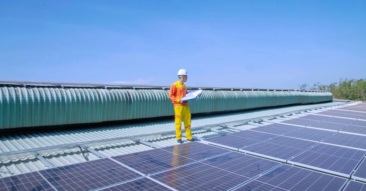 Technicien examinant des panneaux solaires sur un toit, mettant en avant l'énergie renouvelable.