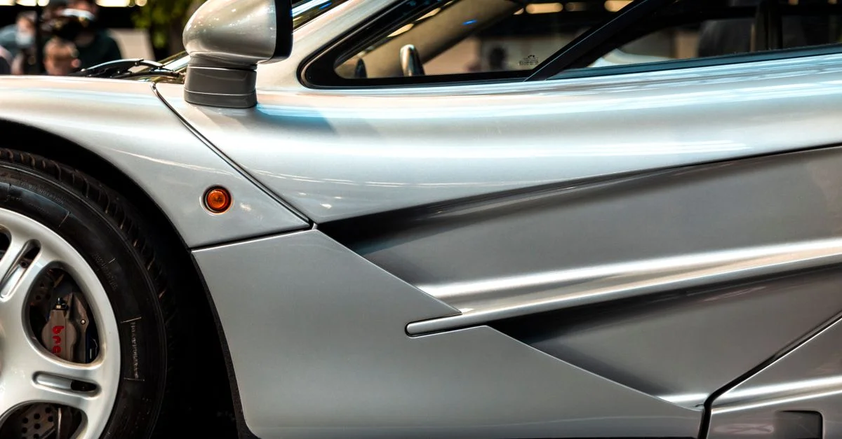 Image détaillée mettant en valeur le design élégant et l'aérodynamisme d'une voiture de sport argentée, soulignant ses courbes et ses détails.
