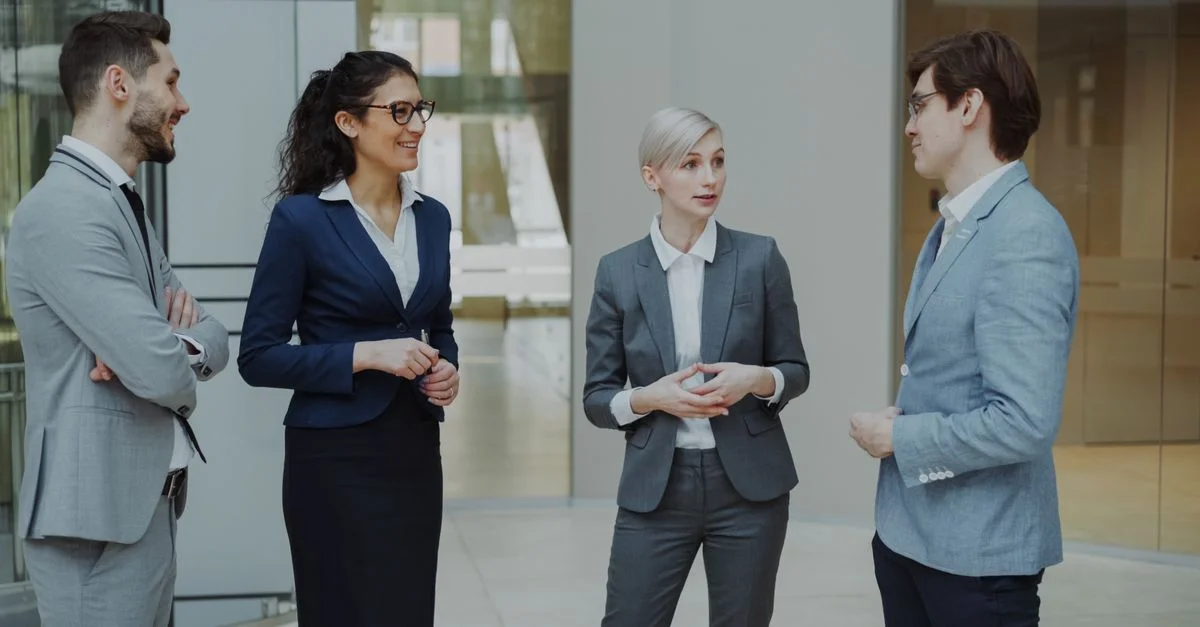 Groupe de professionnels divers ayant une conversation dans un environnement de bureau moderne.