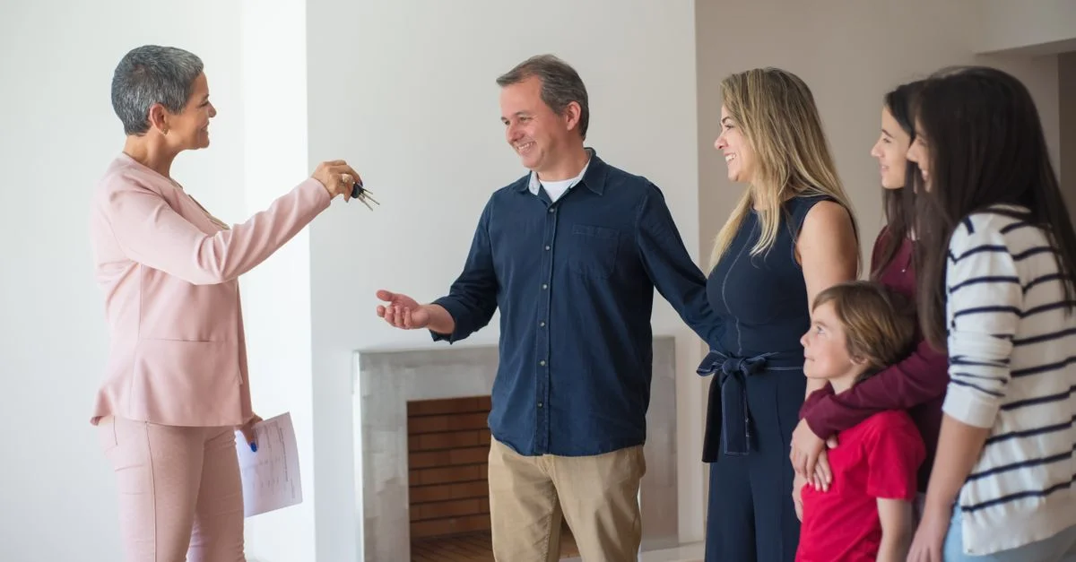 Une famille joyeuse reçoit les clés de sa nouvelle maison d'un agent immobilier à l'intérieur d'une maison moderne.