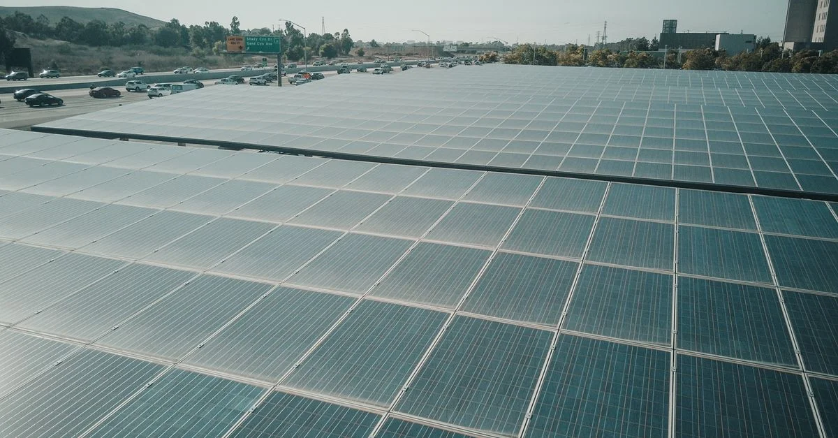Des rangées de panneaux solaires près d'une autoroute captent l'énergie renouvelable sous un ciel dégagé.