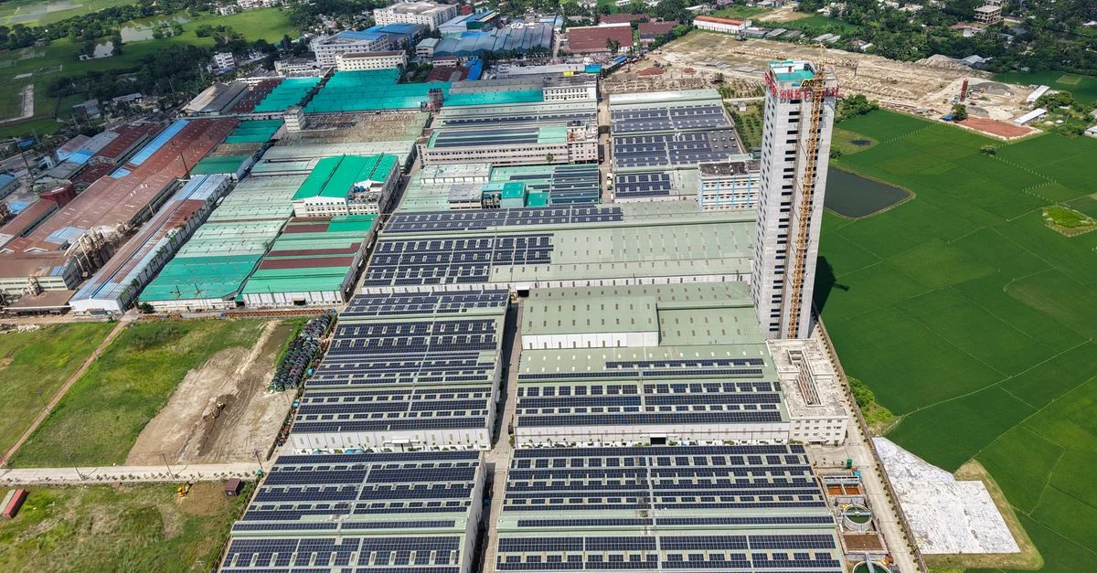 Complexe industriel tentaculaire avec panneaux solaires et champs verts, vu d'en haut.